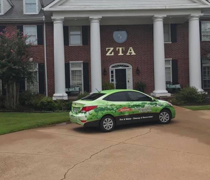 A SERVPRO car in front of a Sorority building.