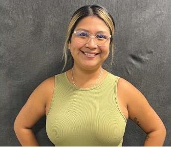 Happy girl with a beautiful smile, black and blonde hair with glasses wearing a green shirt in front of grey screen