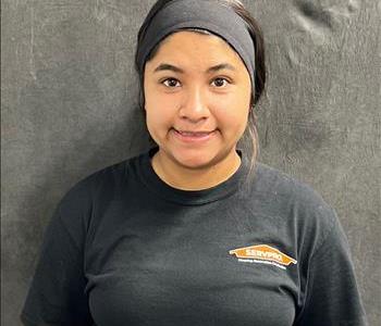 Short girl with black headband, black hair, brown eyes wearing a black shirt in front of a grey screen 