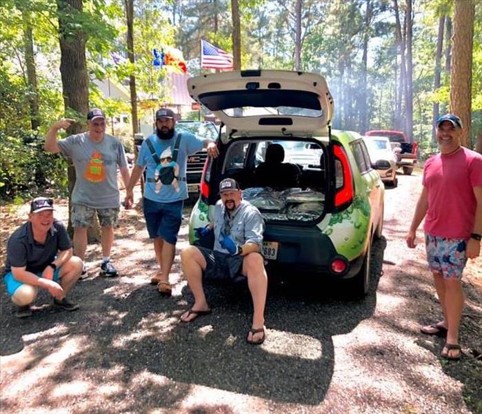 A group of people standing around a SERVPRO vehicle.