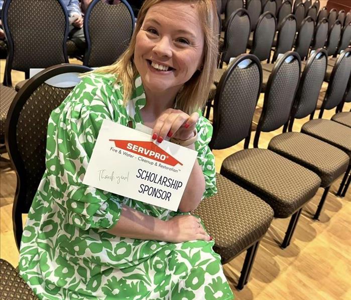 Candice smiling for photo holding the SERVPRO sponsor sign