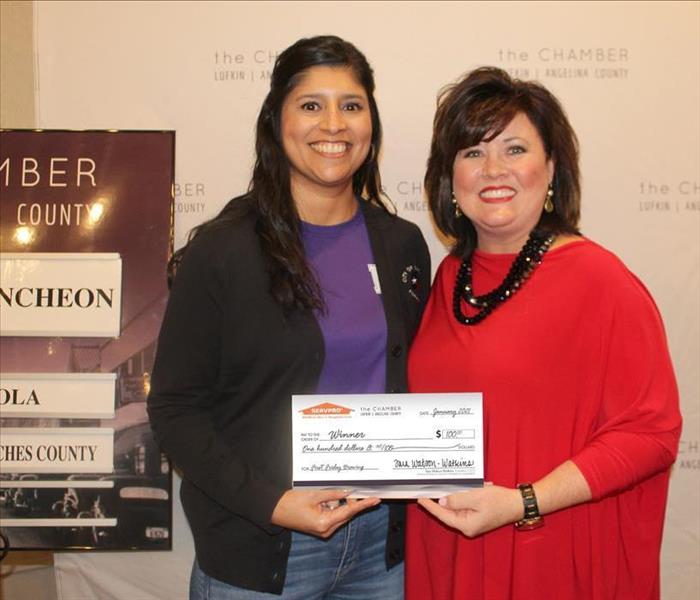Two females holding large check