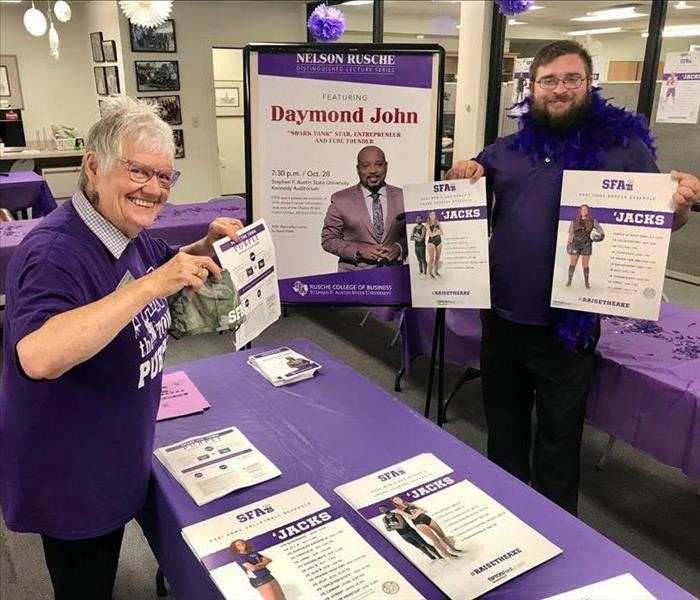 Mary and Dakota hold up SFASU posters