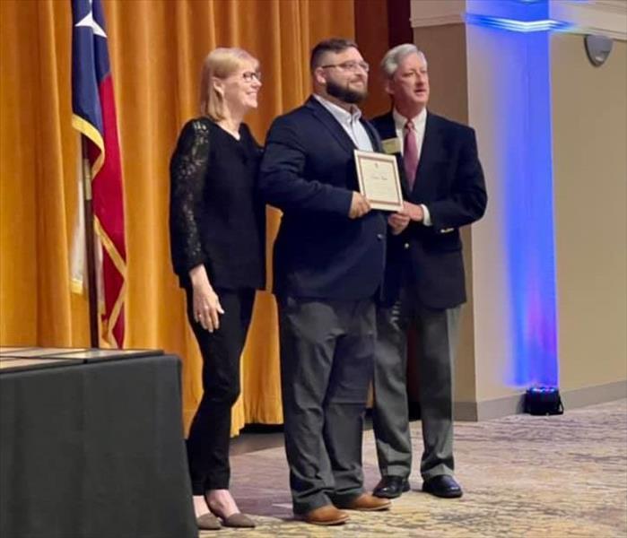 SERVPRO Employee accepting award from two people