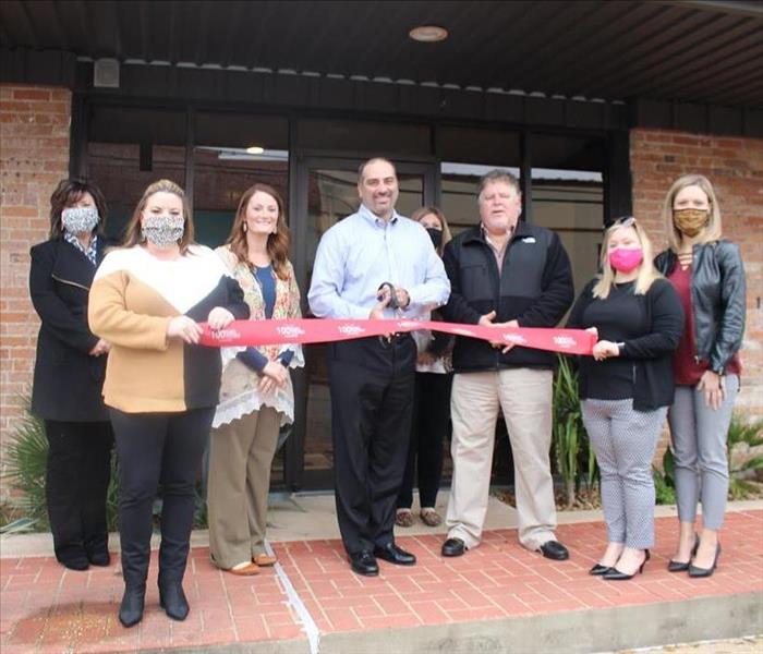 People grouped around cutting a ribbon