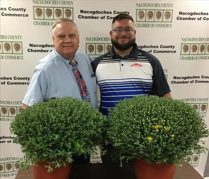 Chamber president and SERVPRO representative holding mums and posing for picture