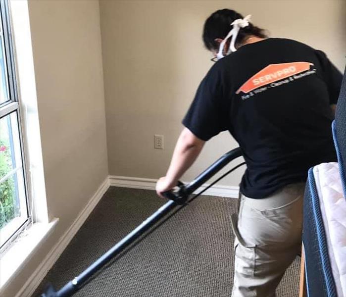 A SERVPRO employee cleans carpeting in a large room.