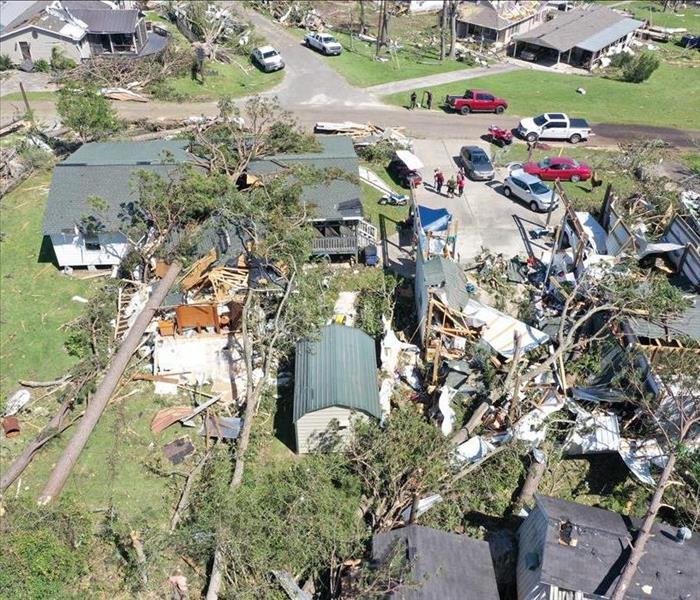 A destroyed house with trees and debris scattered across the home.