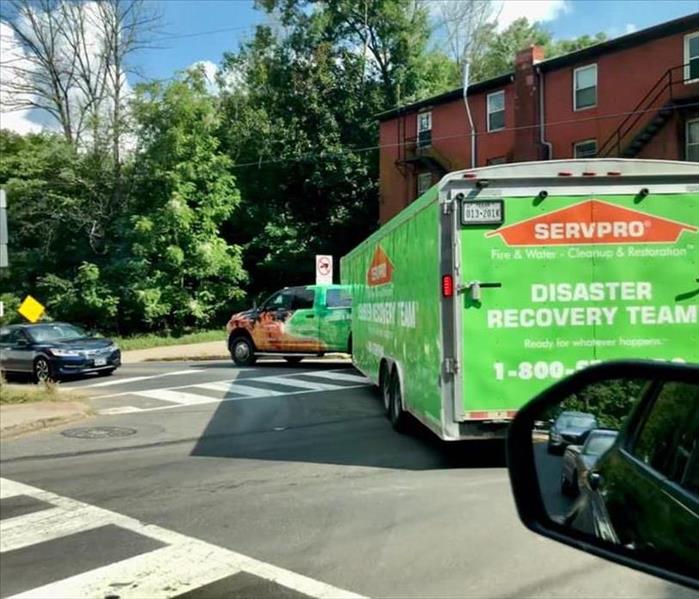 A SERVPRO truck pulling a trailer on a busy street.