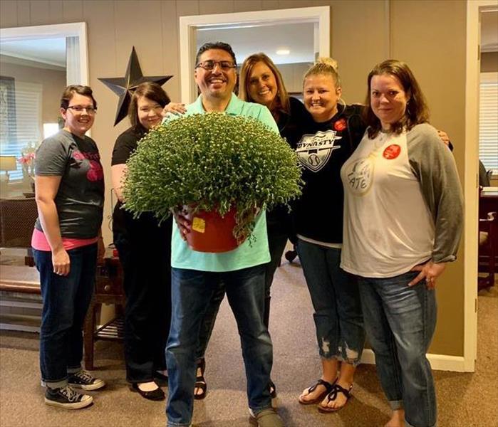 Patrick Castillo posing with customers holding a mum.