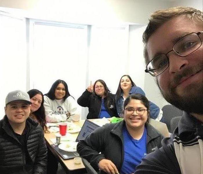 A group of people sitting around a table, posing for a picture.