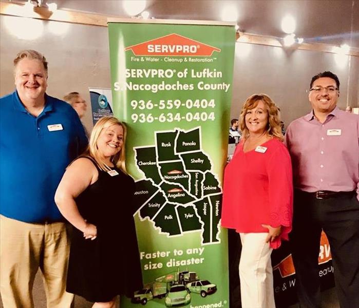 People standing next to a SERVPRO sign.