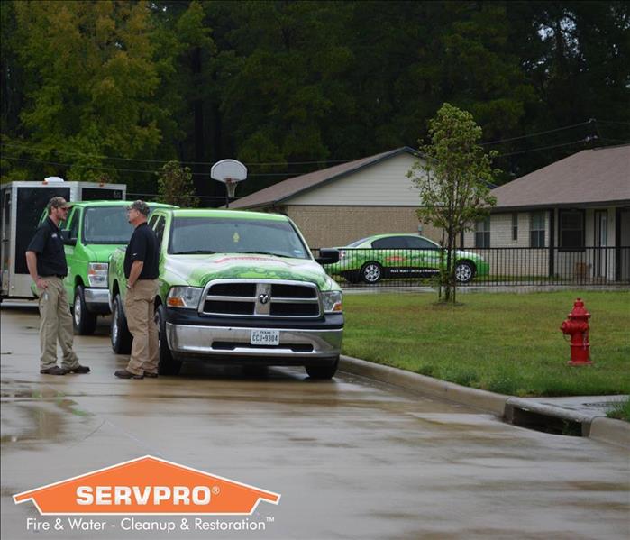 SERVPRO employees standing outside storm damaged home 