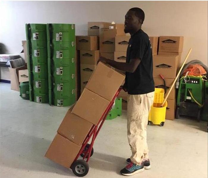 A SERVPRO employee moving large boxes from a home.