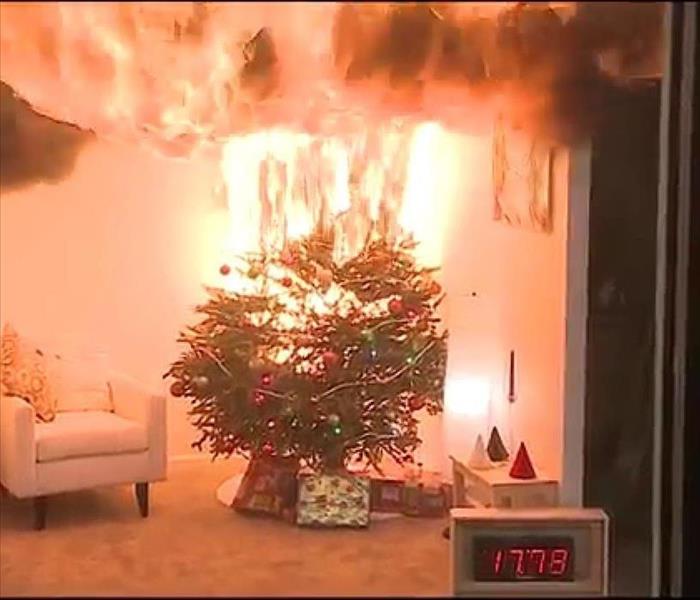 A Christmas tree on fire in a living room of a home.