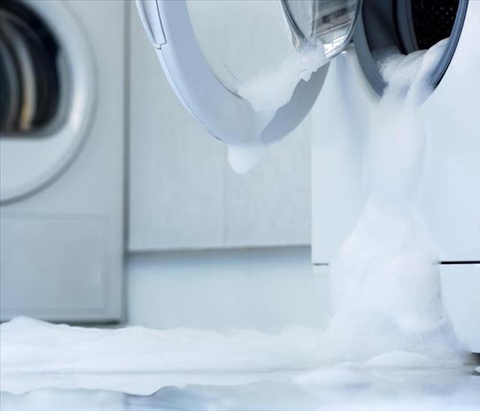 A washing machine that has overflowed and begun to flood.