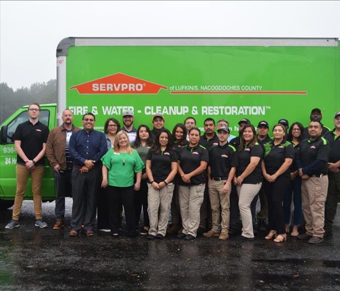 A group picture of employees standing in front of a SERVPRO van.