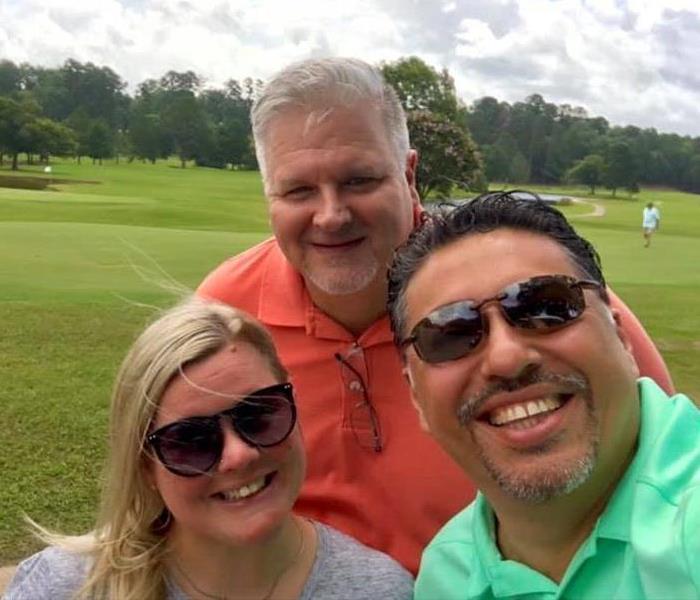 3 People posing for a picture on a golf course.